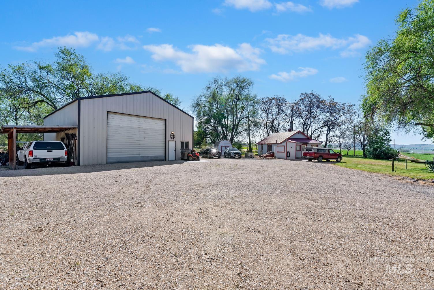 19152 Marsing Road Caldwell, ID 83607 - Photo 31 of 47 Spacious gravel driveway with a large metal workshop featuring a roll-up door and covered lean-to parking