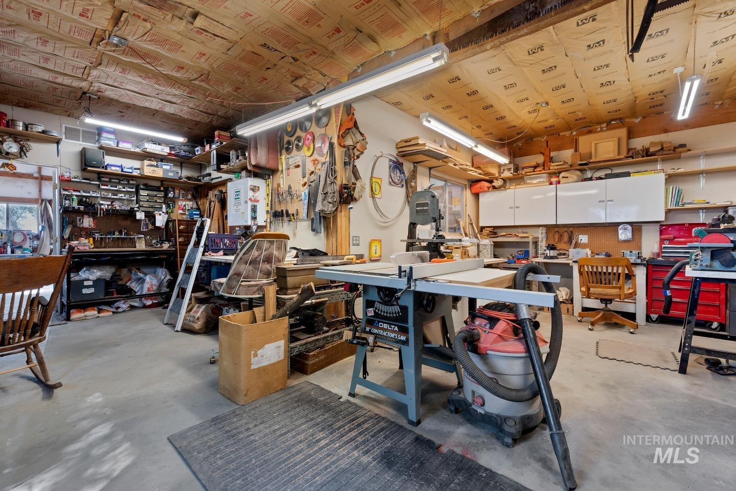 19152 Marsing Road Caldwell, ID 83607 - Photo 34 of 47 Spacious workshop featuring concrete flooring, extensive built-in shelving, overhead fluorescent lighting, and white wall-mounted cabinetry