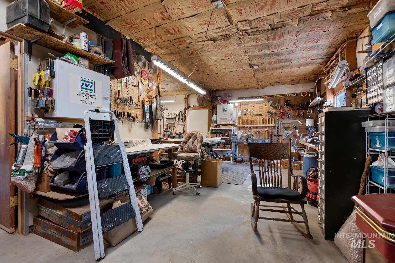 19152 Marsing Road Caldwell, ID 83607 - Photo 35 of 47 Expansive workshop space featuring concrete flooring, exposed ceiling insulation, wall-mounted shelving, and fluorescent lighting