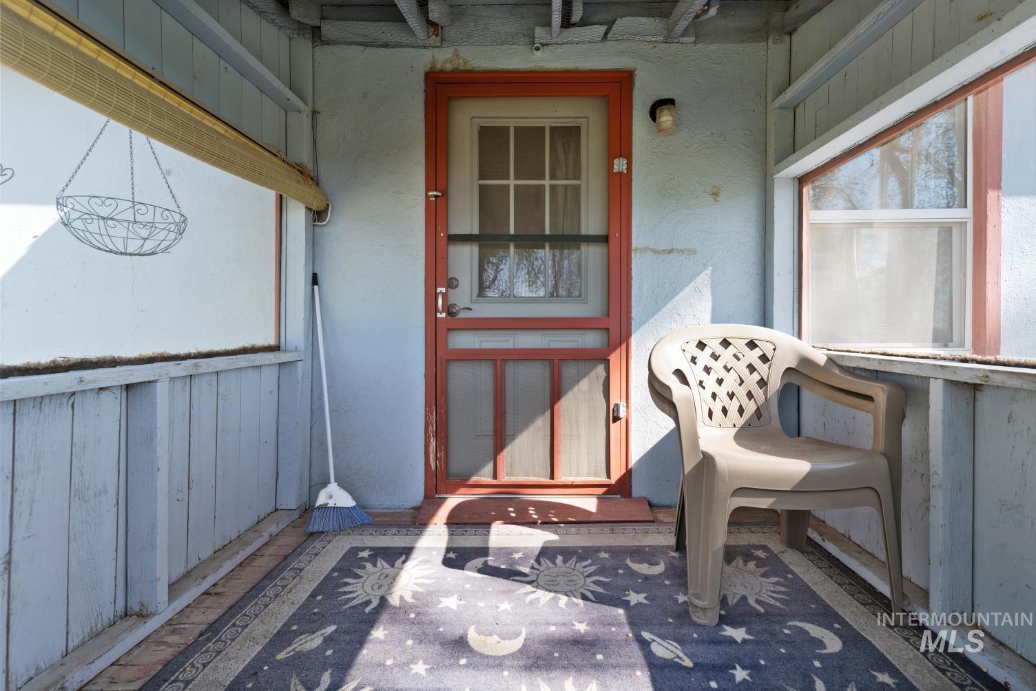 19152 Marsing Road Caldwell, ID 83607 - Photo 39 of 47 Enclosed porch with a red-framed screen door, light blue paneling, and a light-filtering window shade