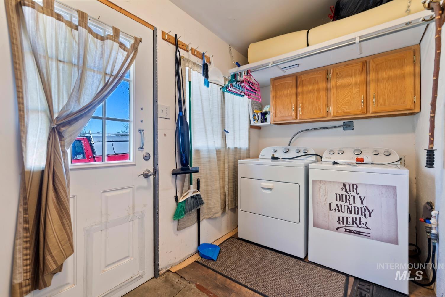 19152 Marsing Road Caldwell, ID 83607 - Photo 40 of 47 Utility area featuring a white paneled door with window, overhead wood cabinetry, and a full-size washer and dryer