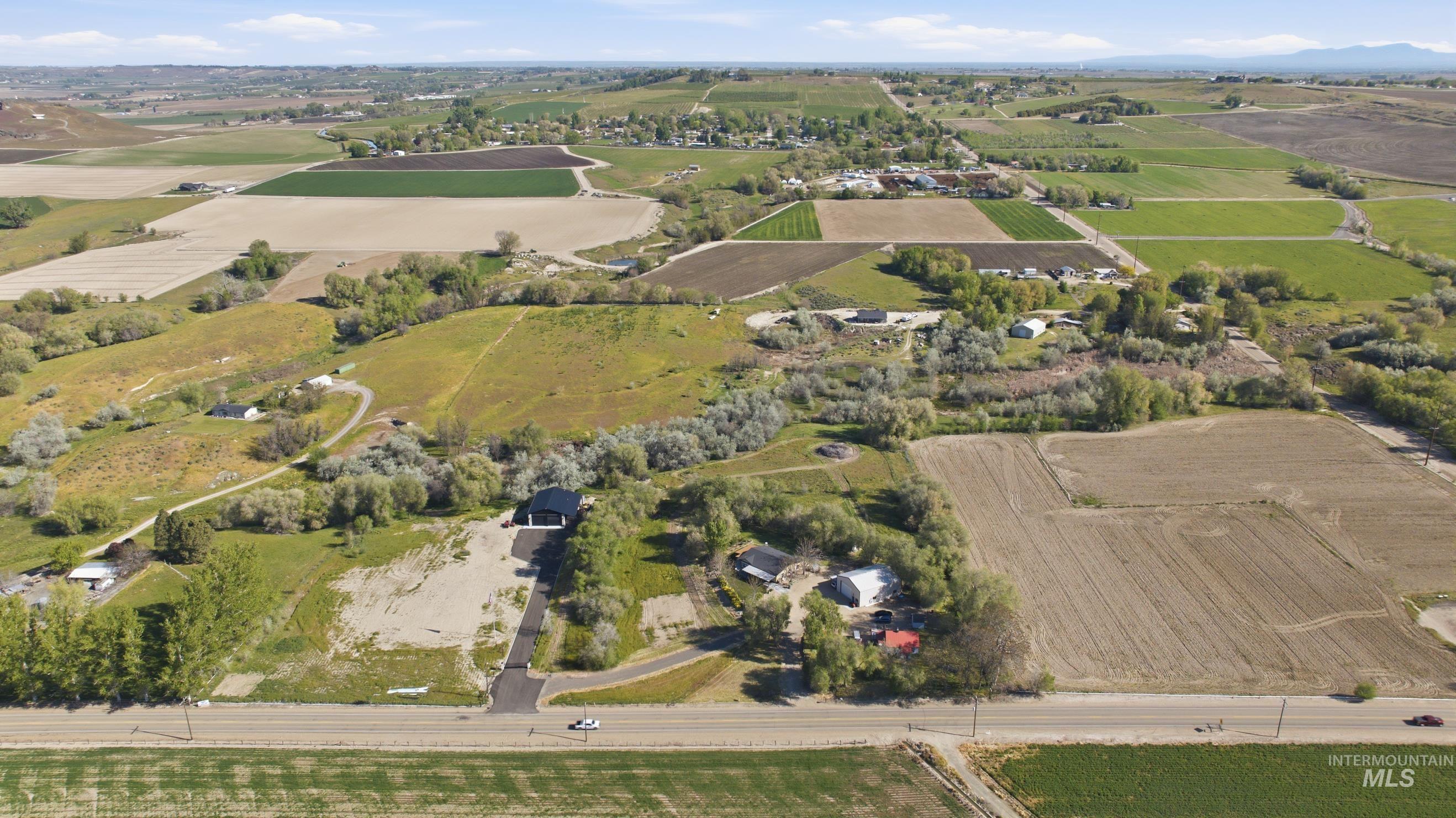 19152 Marsing Road Caldwell, ID 83607 - Photo 45 of 50 Expansive land parcel featuring a paved driveway, a structure with a dark roof, and surrounding agricultural fields
