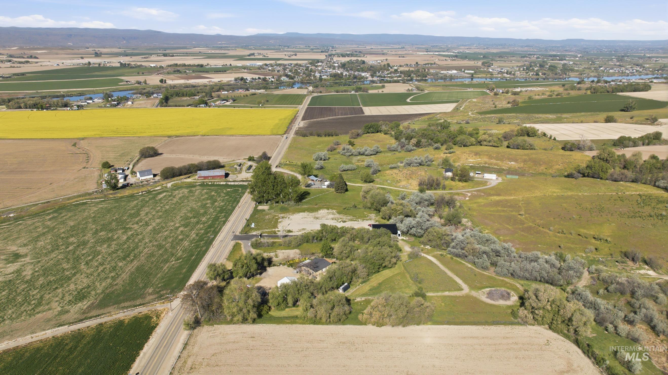 19152 Marsing Road Caldwell, ID 83607 - Photo 47 of 50 Expansive aerial landscape featuring agricultural fields, rolling terrain, scattered buildings, and a distant body of water