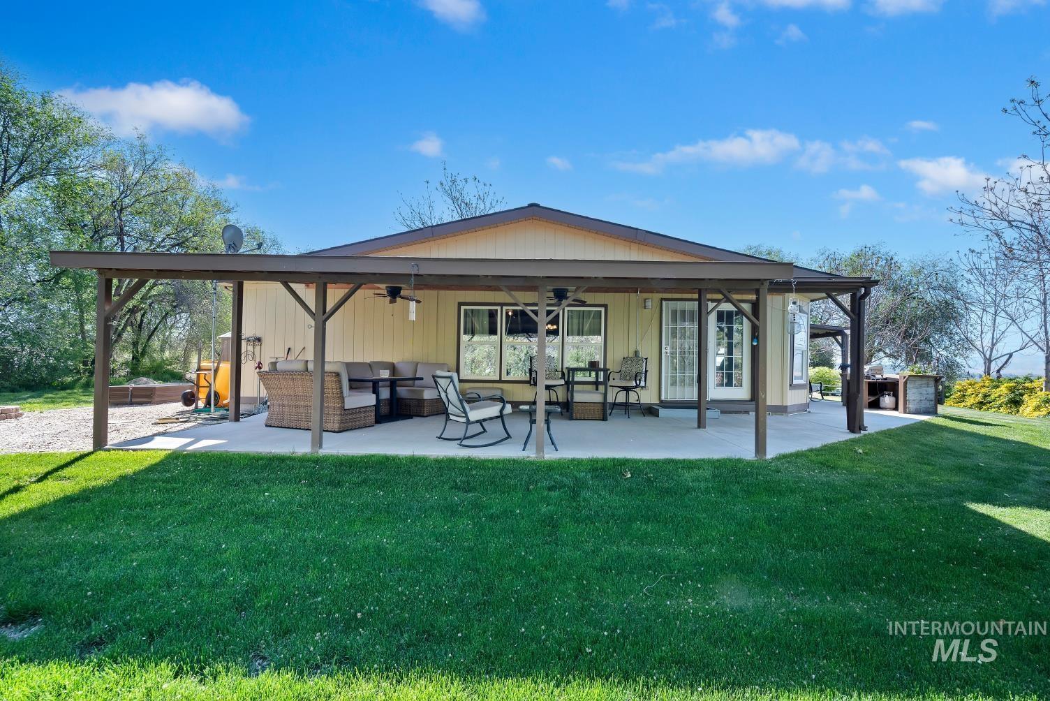 19152 Marsing Road Caldwell, ID 83607 - Photo 5 of 47 Rear exterior featuring a covered concrete patio, a bay window, and exterior door with a glass insert