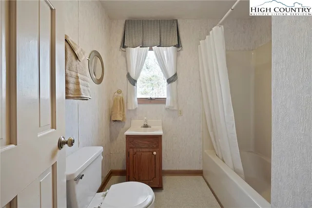 a view of an empty room with a window and a bathroom