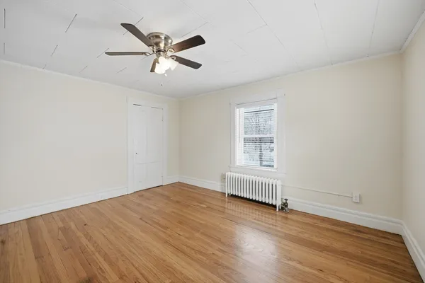 an empty room with wooden floor fan and windows