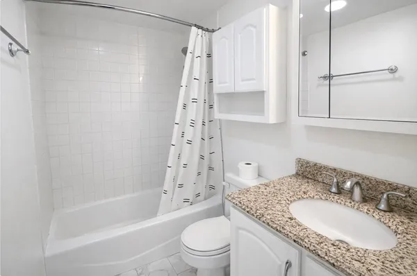 a bathroom with a granite countertop sink toilet and shower
