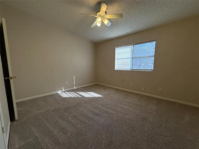 an empty room with a window and a fan