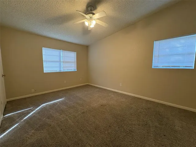 an empty room with windows and fan