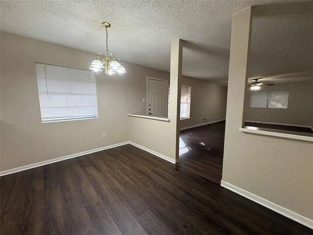 an empty room with wooden floor chandelier and windows