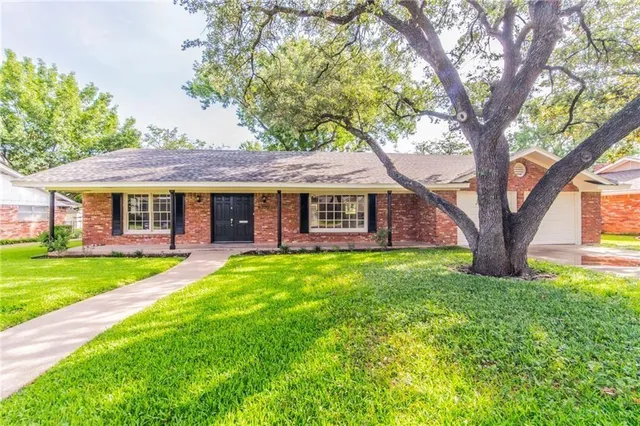 a view of a yard in front of a house with a large tree