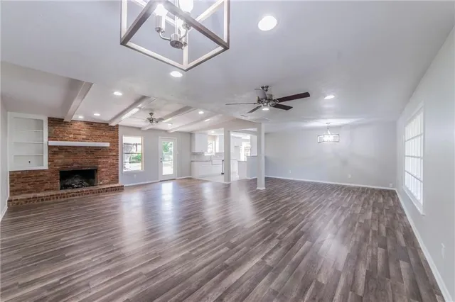 an empty room with wooden floor fireplace and windows