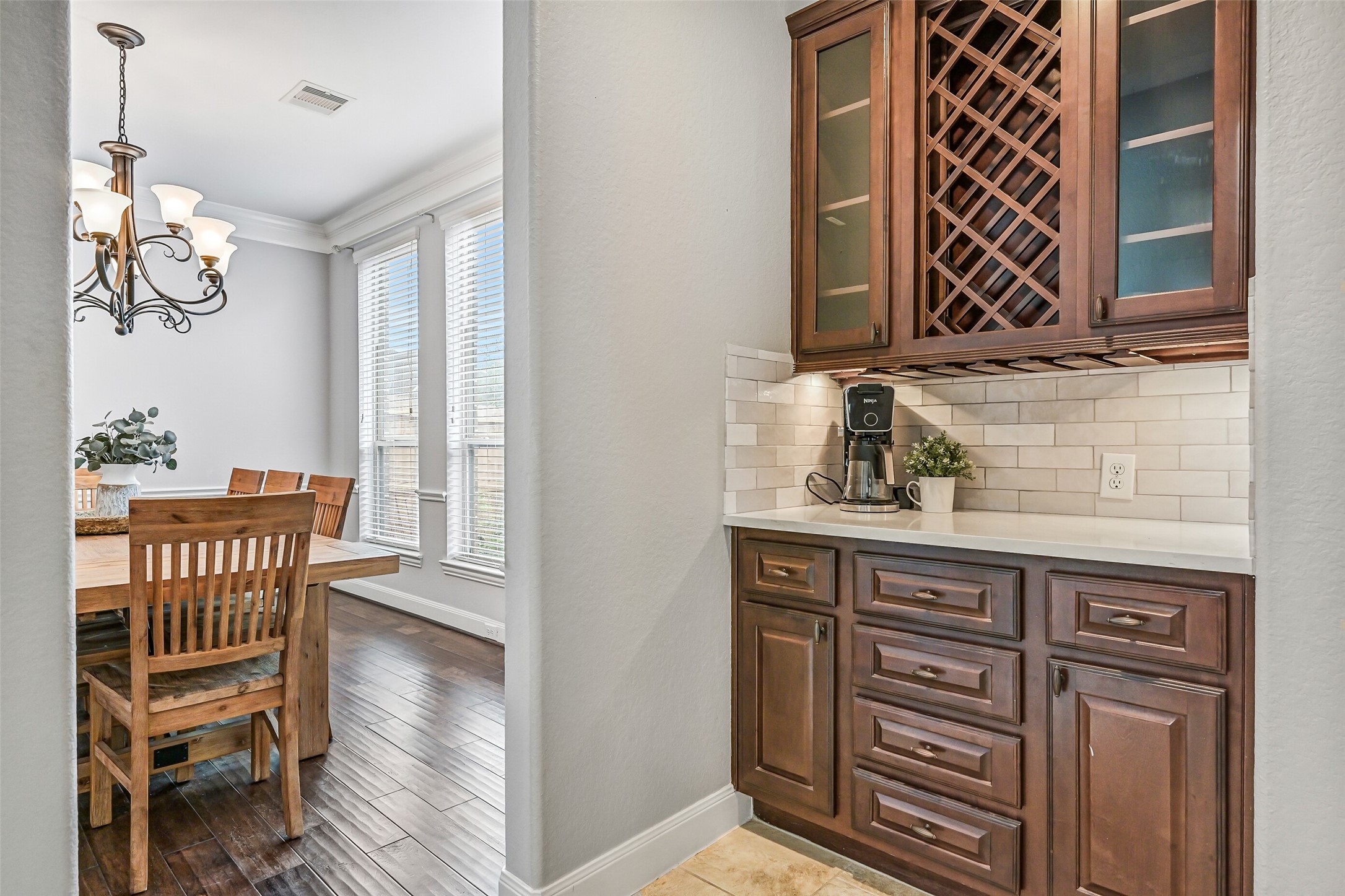 1008 Point Isabel Lane Friendswood, TX 77546 - Photo 12 of 50 Connecting the dining room to the kitchen, a built-in serving area provides additional cabinetry and counter space, ideal for staging meals, storage, or use as a beverage station during gatherings.