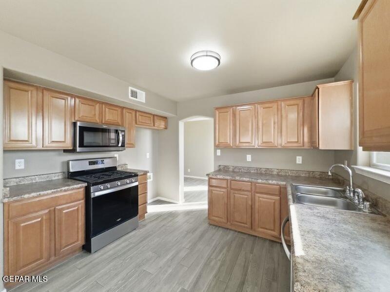 533 Flanagan Place El Paso, TX 79928 - Photo 19 of 52 a kitchen with stainless steel appliances granite countertop wooden cabinets a sink dishwasher a stove and a refrigerator with wooden floor