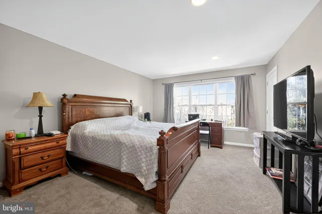 a bedroom with a bed and a flat tv screen on the dresser