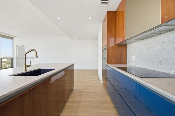 a view of a kitchen with kitchen island a sink wooden floor and a large window