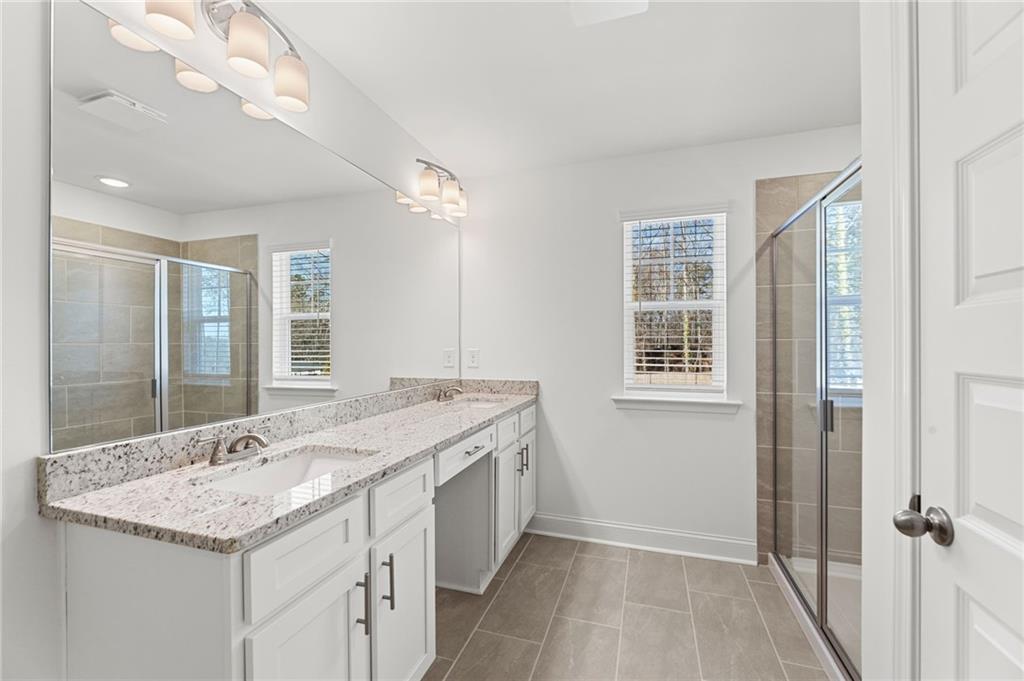 5629 Overview Drive Flowery Branch, GA 30542 - Photo 10 of 25 a bathroom with a granite countertop sink a mirror and a shower