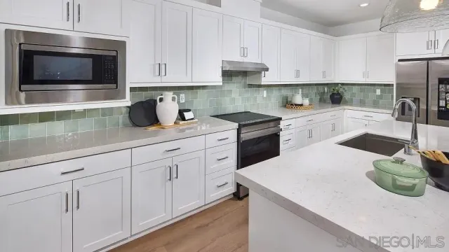 a kitchen with granite countertop white cabinets and stainless steel appliances