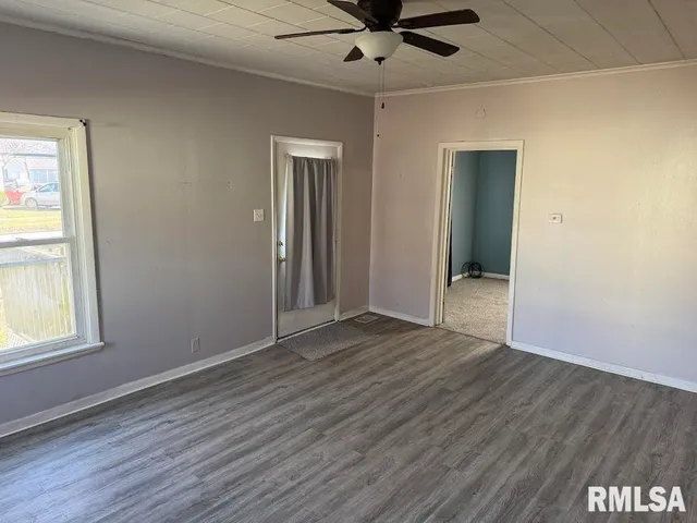 a view of an empty room with wooden floor and a window
