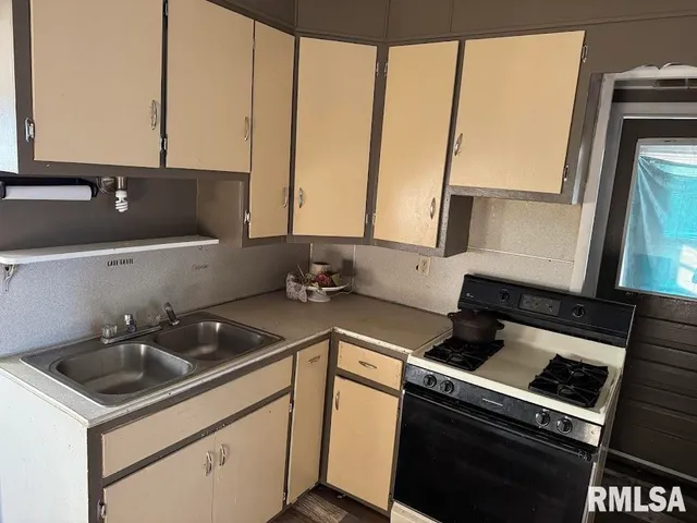 a kitchen that has a sink a stove and a microwave