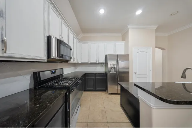 a kitchen with stainless steel appliances a sink a stove a microwave a refrigerator a sink and cabinets