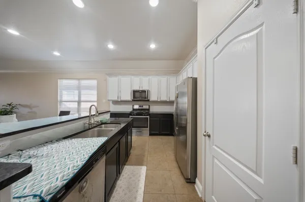 a kitchen with stainless steel appliances kitchen island granite countertop a stove top oven a sink and a refrigerator