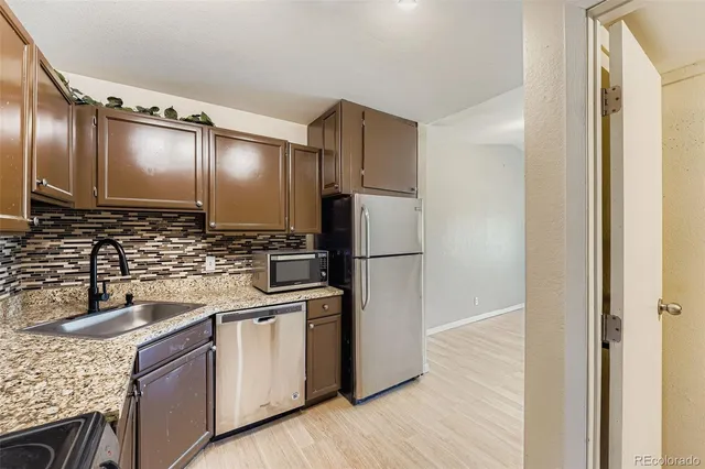 a kitchen with stainless steel appliances granite countertop a refrigerator and a sink