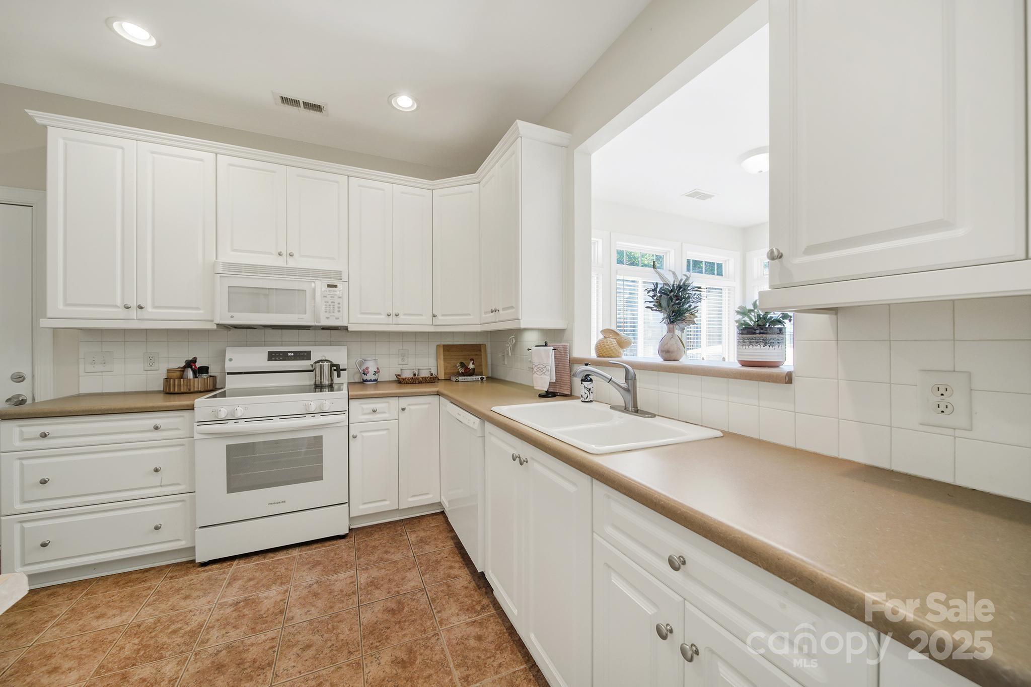 2959 Bellasera Way Matthews, NC 28105 - Photo 9 of 30 a kitchen with granite countertop white cabinets white appliances and sink