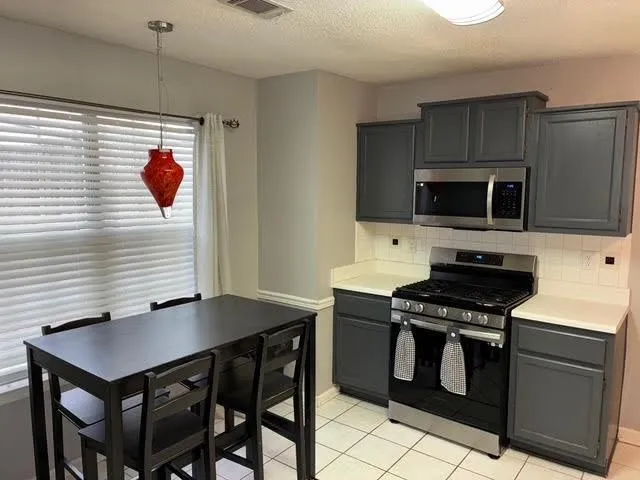 a kitchen with a stove a sink and chairs
