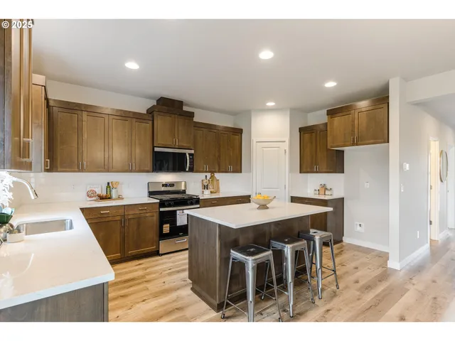 a kitchen with stainless steel appliances granite countertop a sink a stove a refrigerator a dining table and chairs