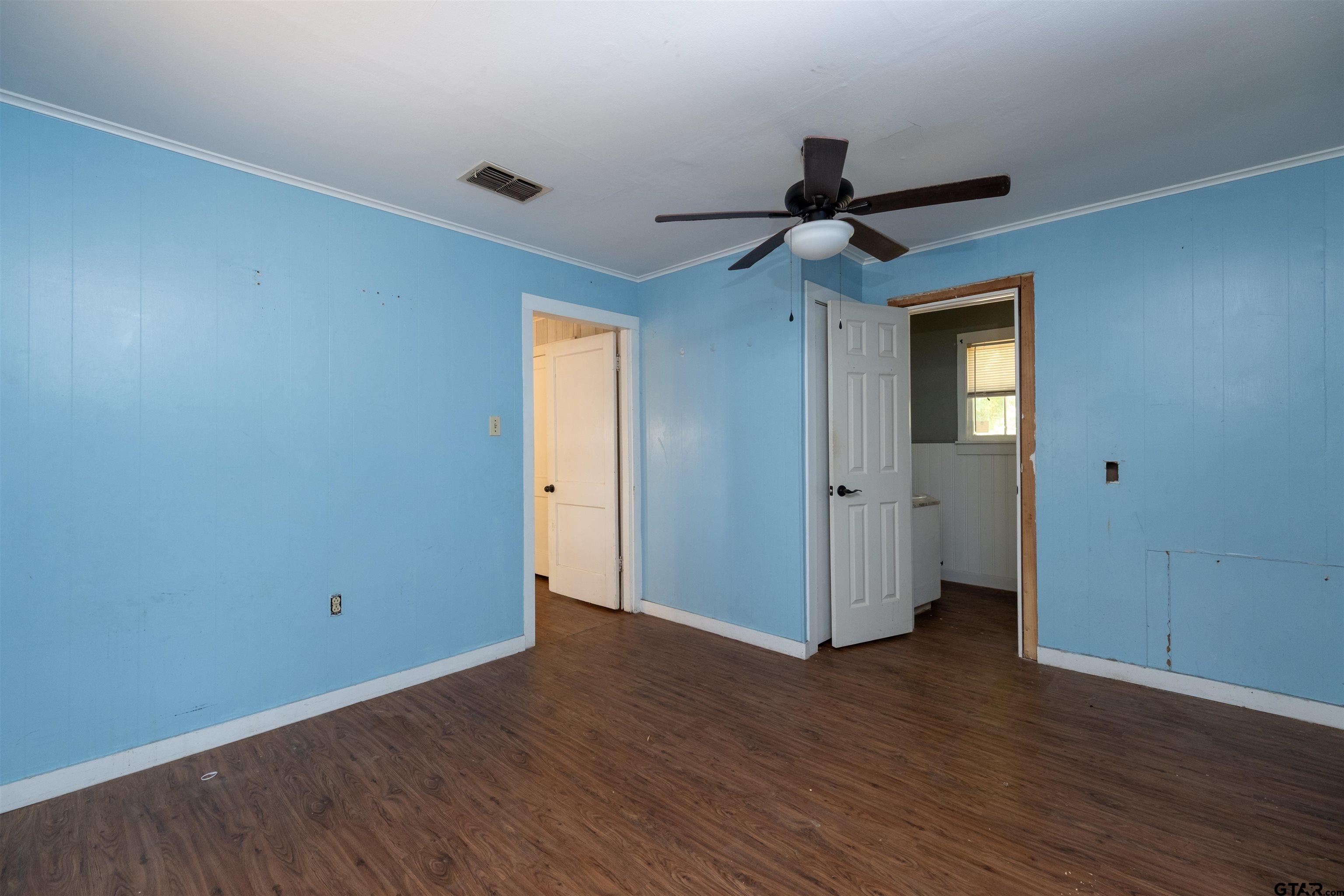 a view of a hallway with wooden floor and a chandelier fan