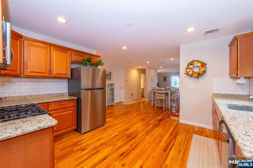 a kitchen with stainless steel appliances granite countertop a refrigerator and a stove top oven