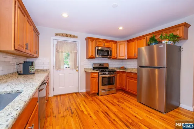 a kitchen with granite countertop wooden floors stainless steel appliances and a window