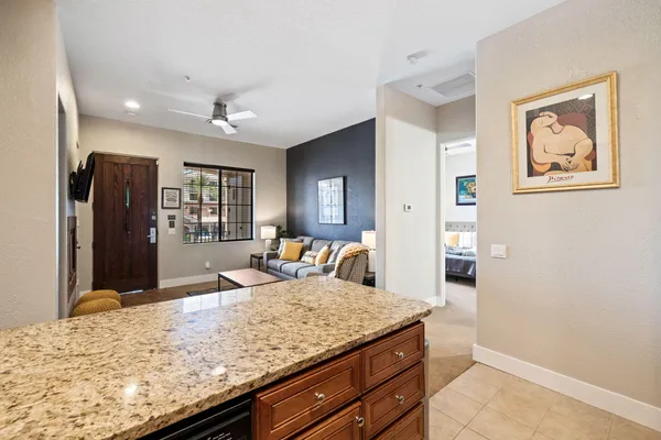 a living room with stainless steel appliances kitchen island granite countertop a refrigerator and wooden cabinets