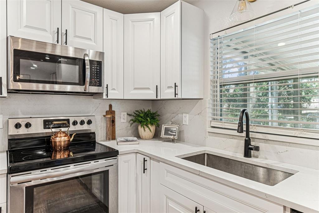727 Locust Street Tarpon Springs, FL 34689 - Photo 13 of 47 a kitchen with white cabinets a sink and a stove with wooden floor
