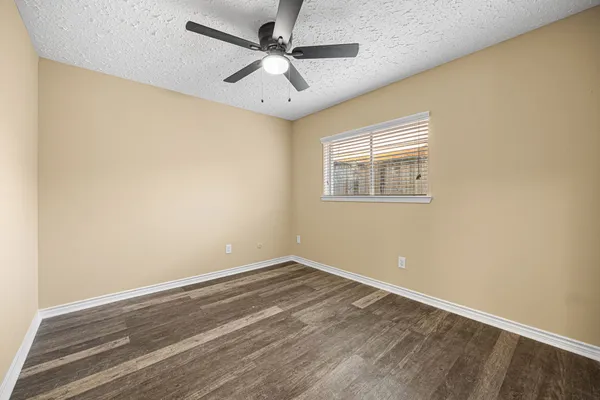 en empty room with wooden floor and ceiling fan