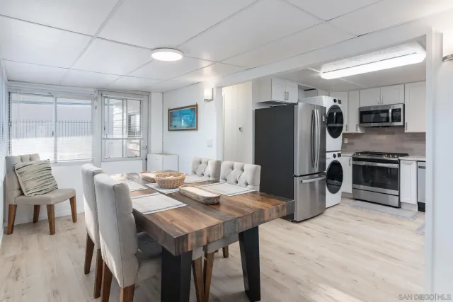 a kitchen with stainless steel appliances kitchen island granite countertop a refrigerator a stove a sink a dining table and chairs with wooden floor