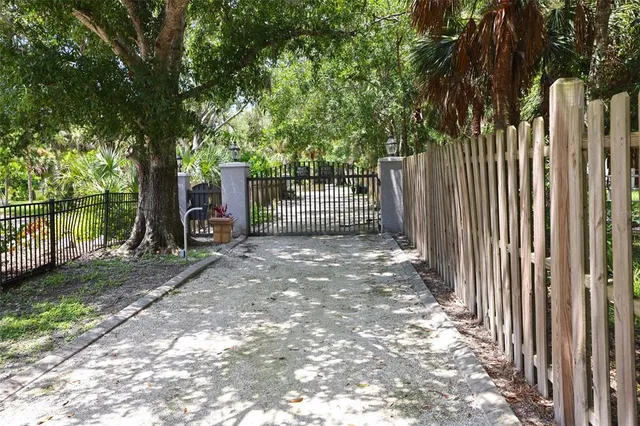 a view of a backyard with large trees and wooden fence