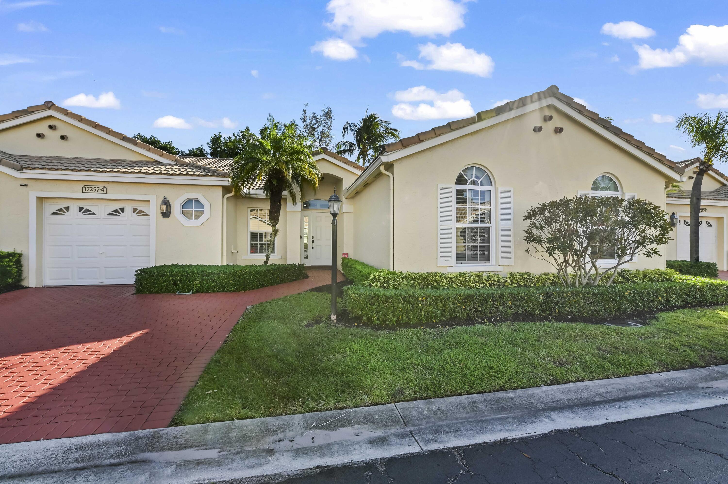 a view of a white house with a big yard and potted plants
