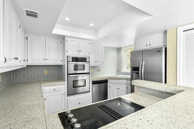 a kitchen with stainless steel appliances kitchen island granite countertop a refrigerator and a sink