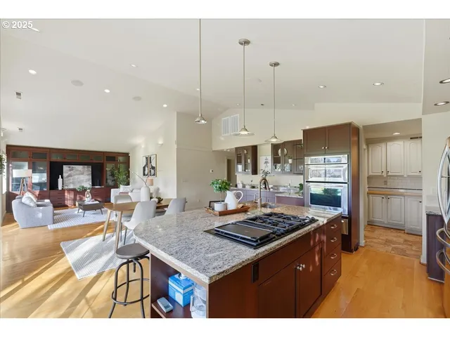 a kitchen with a stove a refrigerator a sink a dining table and chairs with wooden floor