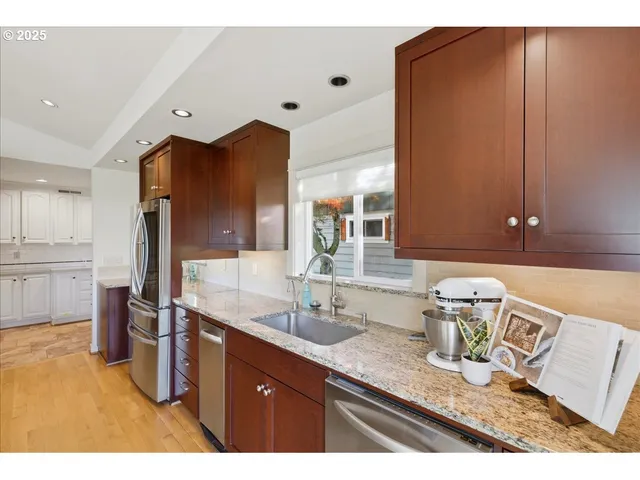a kitchen with stainless steel appliances granite countertop a sink refrigerator and cabinets