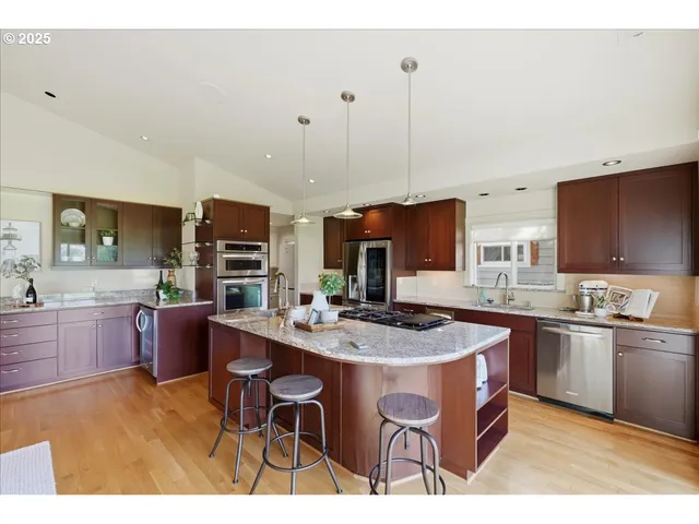 a kitchen with stainless steel appliances granite countertop a sink a stove a dining table and chairs