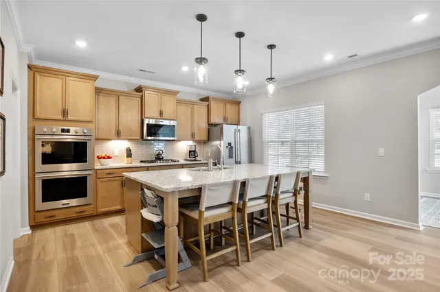 a kitchen with stainless steel appliances granite countertop a stove top oven a refrigerator a sink and a dining table with wooden floor