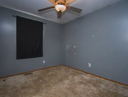 an empty room with a chandelier fan
