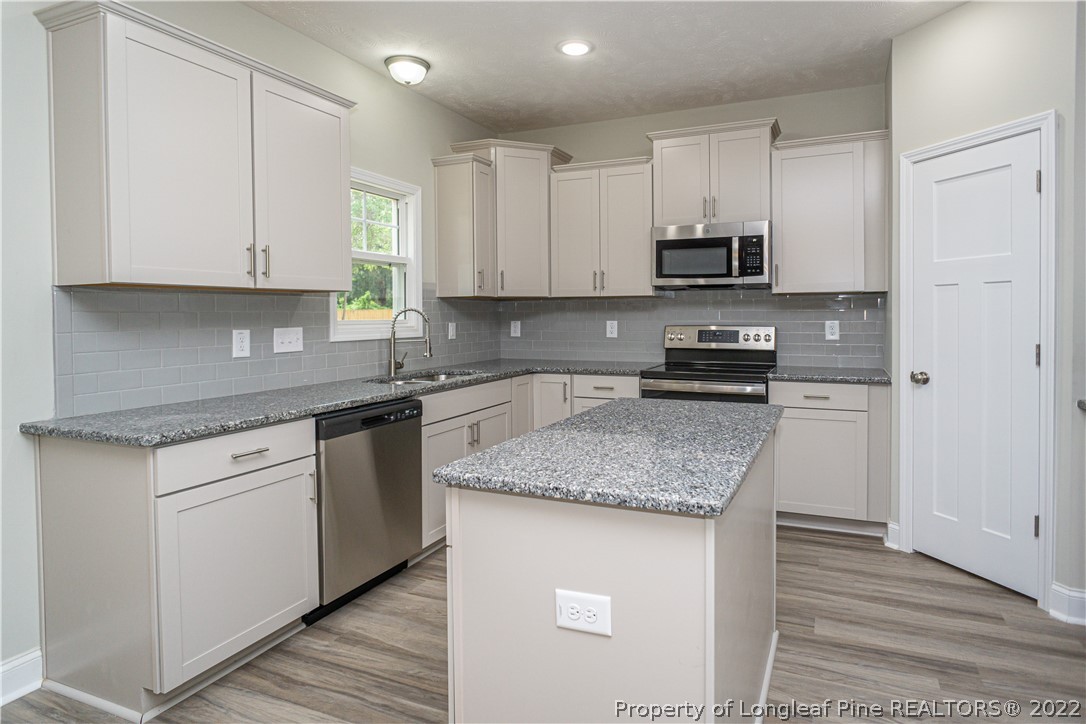 1628 Strickland Bridge Road Fayetteville, NC 28304 - Photo 13 of 34 a kitchen with stainless steel appliances granite countertop a sink stove and refrigerator
