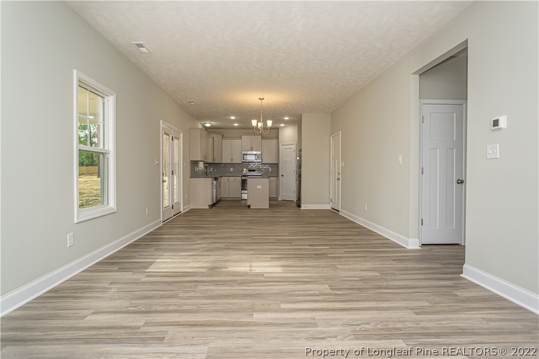 1628 Strickland Bridge Road Fayetteville, NC 28304 - Photo 9 of 34 a view of kitchen and empty room with wooden floor