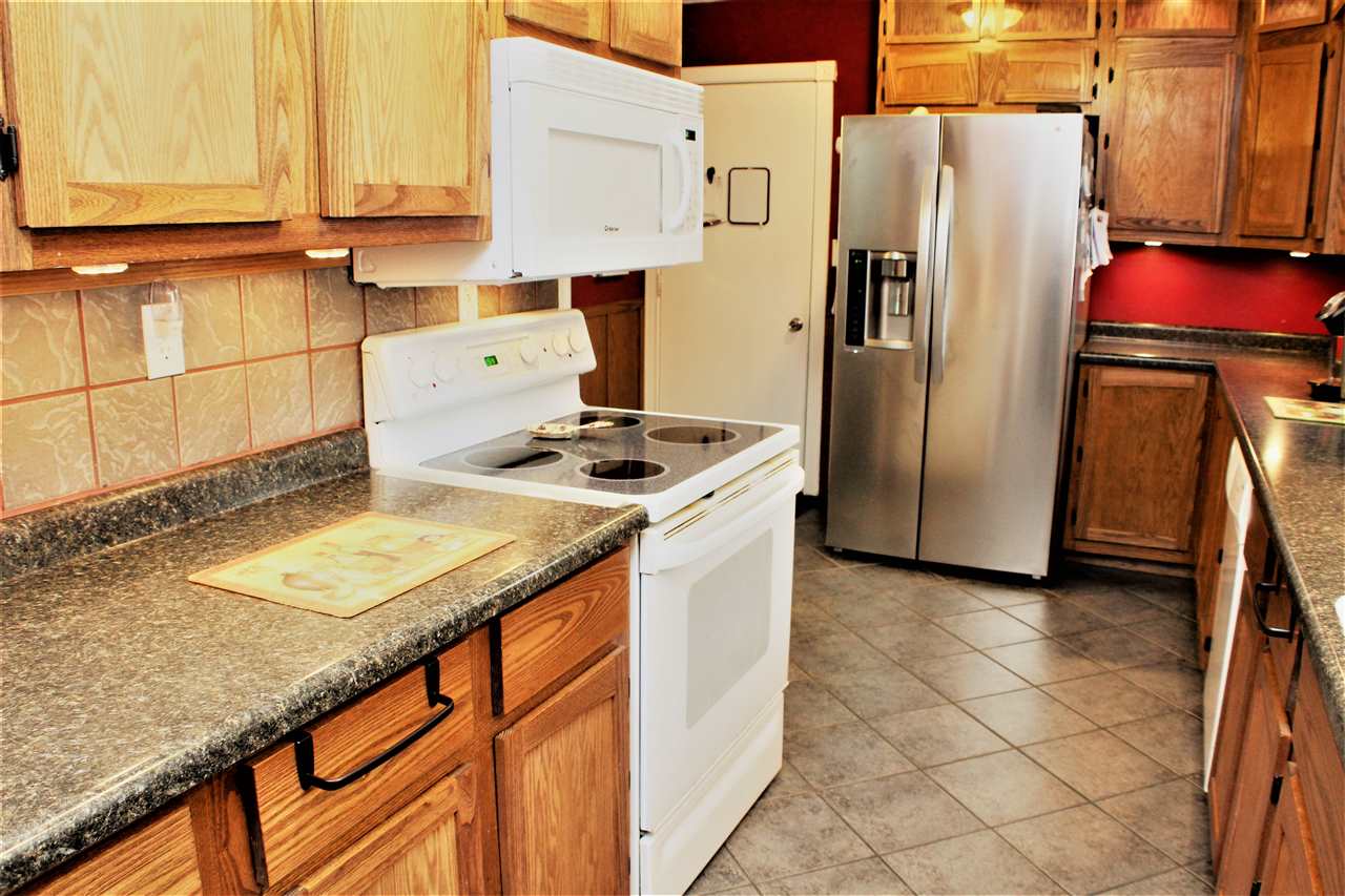 10619 Grover Oaks Road Roscoe, IL 61073 - Photo 14 of 24 a kitchen with stainless steel appliances granite countertop a refrigerator a sink and a stove