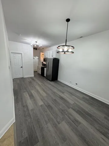 a view of a room with a hanging light and hardwood