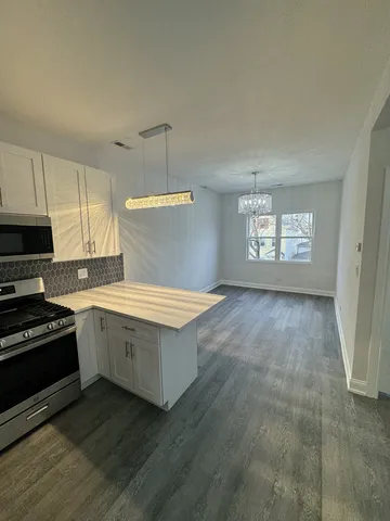 a kitchen with granite countertop a stove a sink and white cabinets